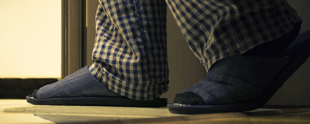 Adult man in pajamas walks to a bathroom at the night